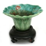 A Chinese small lotus leaf shaped vase or brush washer on a hardwood stand, 5cms (2ins) high.