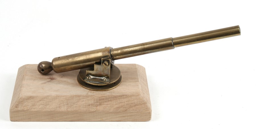 An early 20th century brass signal cannon on a rotating mount, mounted on a modern hardwood base.