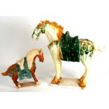 A large Chinese Tang style horse, 51cms (20ins) high; together with a similar smaller, 29cms (11.