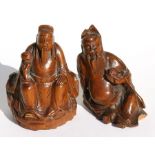 An 18th century Chinese carved wooden figure in the form of a seated robed man holding a rui
