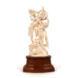 An early 20th century Indian ivory group, a deity with a semi naked woman, mounted on a hardwood