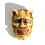 A 19th century Japanese carved ivory netsuke in the form of an oni mask, signed 'Gyokuzan', 2.