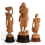 Three Indian carved wooden figures depicting peasant women on hardwood plinths, the largest 25cms (