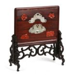 A Chinese hardwood table screen inset with jade and carnelian, on a pierced hardwood stand, 17cms (