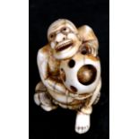 A late 18th / early 19th century Japanese ivory netsuke in the form of a man holding a ball with a