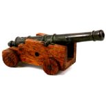 A small bronze signal cannon mounted on a wooden carriage. The barrel is 10cms (4ins) long with an