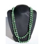 A long graduated figured jade bead necklace, 137cms (54ins) total length.