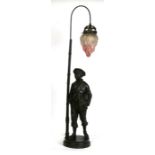 A bronzed spelter figural lamp in the form of a young boy holding a book beside a lamp post,