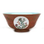 A Chinese bowl decorated with flowers within panels, with gilded foliate scrolls on an orange