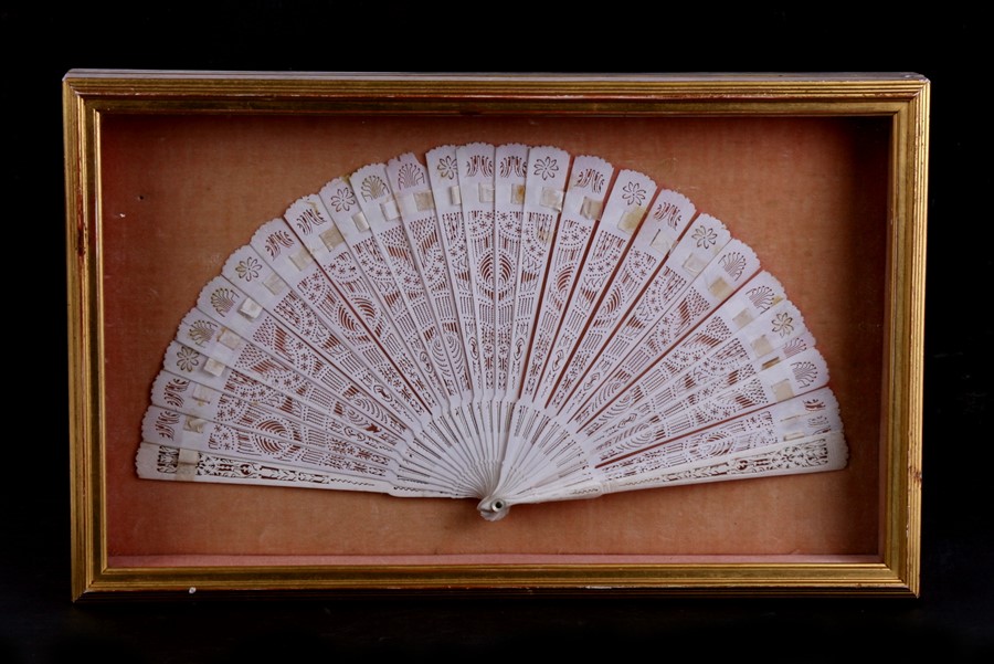 A Chinese Canton Export pierced bone brise fan, 30cms (12ins) wide, mounted in a glazed display case