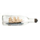 A three masted ship in a bottle, 29cms (11.5ins) long.