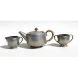 A Liberty & Co. Tudric hammered pewter three-piece teaset comprising a teapot, milk jug and sugar