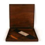 A walnut technical drawing box containing slide rule, parallel rule and squares, 46cms (18ins)