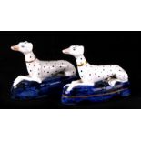 A pair of Staffordshire pottery ‘long dog’ Dalmatian pen stands, each modelled lying on a blue