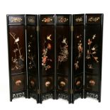 A Chinese six-fold black lacquer screen, the panels inlaid with hardstone depicting birds on