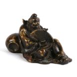 An Asia bronze depicting a reclining gentleman holding a fan, 16.5cms (6.5ins) wide.Condition