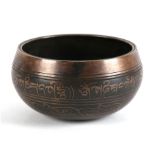 A Tibetan bronze singing bowl decorated with Sanskrit, 12cms (4.25ins) diameter.