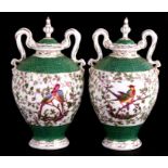 A pair of continental two-handled urns and covers decorated with birds amongst foliage, 28cms (