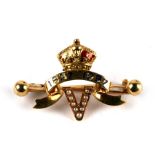 An 18ct gold and enamel brooch set with seed pearls depicting the letter V below a scroll and crown,