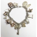 A silver bracelet of solid curb links, with numerous charms attached, 68 g gross