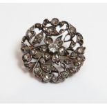 A diamond cluster brooch, the central diamond and rose cuts throughout set in silver, with a later