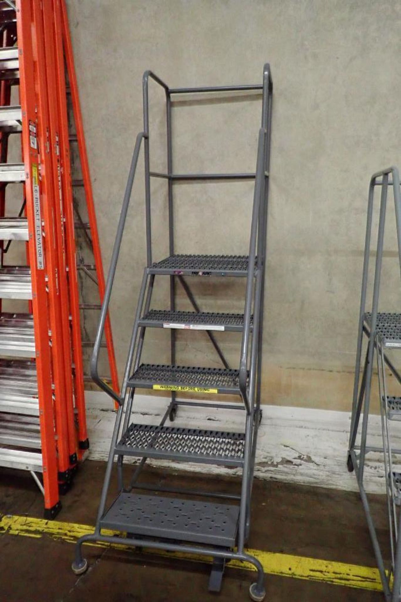 Tri Arc 5-step mild steel rolling warehouse ladder. **Rigging Fee: $50**