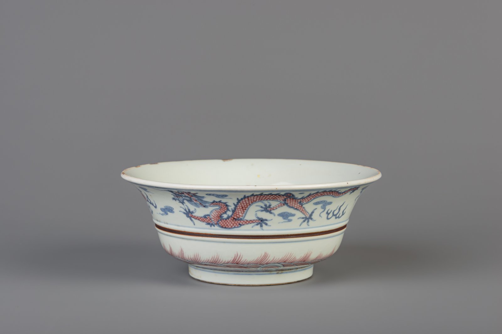 A Chinese blue, white and copper red 'dragon and phoenix' bowl, Kangxi mark, 19th/20th C.