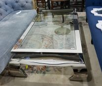 Contemporary designer stainless steel coffee table with inset plate glass top and raised on scroll