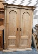 Old pine wardrobe of architectural design, the pair of arched panelled doors enclosing shelves and