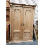 Old pine wardrobe of architectural design, the pair of arched panelled doors enclosing shelves and