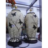 Two porcelain bodied table lamps decorated with butterflies amongst foliage, a potted faux plant of