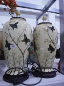 Two porcelain bodied table lamps decorated with butterflies amongst foliage, a potted faux plant of