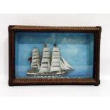 Model of a three-masted sailing ship in a wooden framed glass case