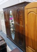 Edwardian sheraton-style mahogany triple wardrobe, the oval mirror plate central door flanked by