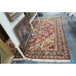 Large Persian style wool carpet, the brick red ground with large foliate medallion and spandrels,