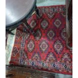 Red ground Eastern rug with central field decorated with elephant foot guls, motif patterned border,