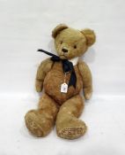Large gold plush straw stuffed bear with glass eyes and stitched nose with collar and black bow,