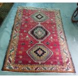 Red ground Eastern style floor rug with three central stepped medallions to a stepped border,