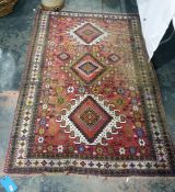 Caucasian style wool rug having three hooked lozenge shaped medallions to the cherry red field,