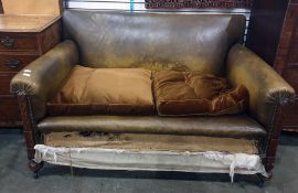 Early 20th century oak framed brown leather two-seat sofa on turned supports to castors