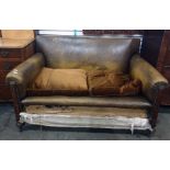 Early 20th century oak framed brown leather two-seat sofa on turned supports to castors