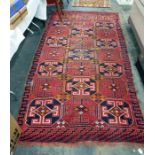 Caucasian style wool rug with rows of three hexagonal elephants foot guls, on a red brick ground,