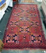 Caucasian style wool rug with rows of three hexagonal elephants foot guls, on a red brick ground,