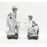Two Lladro figures of geishas, one bending towards a flowering tree in a pot, the other crouching