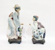 Two Lladro figures of geishas, one bending towards a flowering tree in a pot, the other crouching