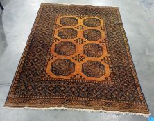 Mustard ground Eastern style floor rug with elephant foot central medallions to a stepped border,