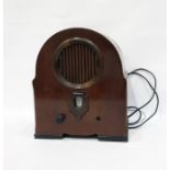 Mahogany cased transistor radio in shaped oval case, with fretwork grille and dial beneath