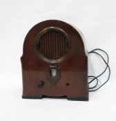 Mahogany cased transistor radio in shaped oval case, with fretwork grille and dial beneath