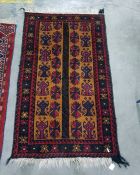 Mustard ground Eastern rug with red and blue repeating motifs either side of a central black