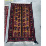 Mustard ground Eastern rug with red and blue repeating motifs either side of a central black